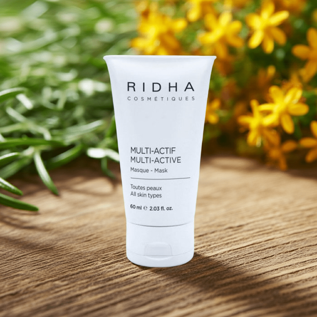 Tube de masque multi actif pour le visage toutes peaux déposé sur une surface en bois avec fleurs jaunes en arrière-plan