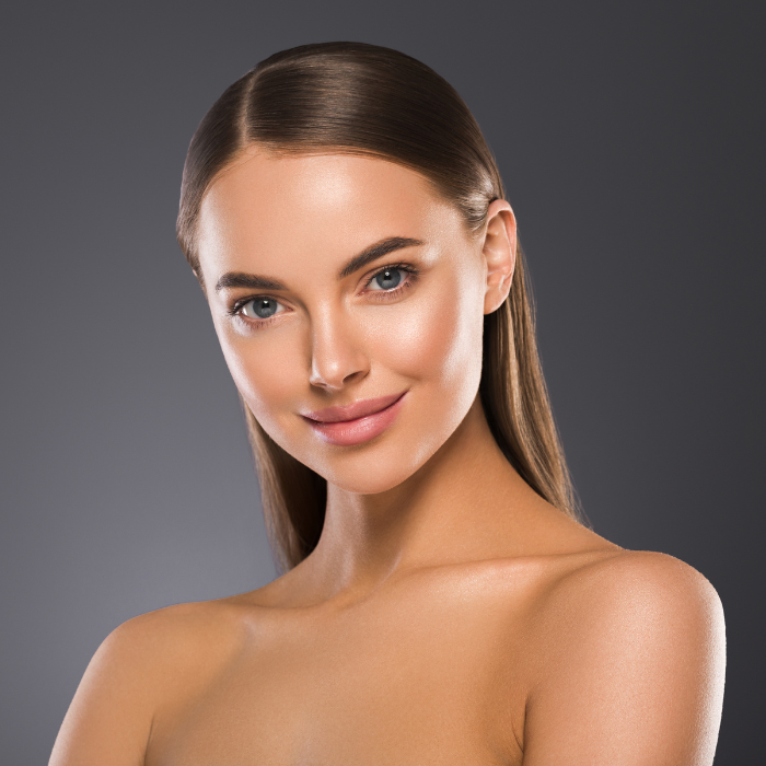 Visage de femme aux cheveux longs bruns, épaules dénudées avec une peau lumineuse.